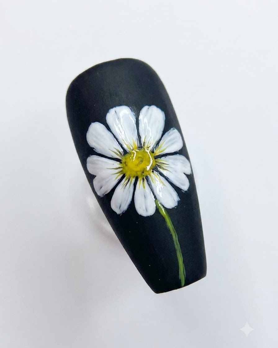 Ein fertiges Nail-Art-Design auf einem schwarzen Nagel mit einem detaillierten weißen Gänseblümchen, gelbem Zentrum und grünem Stiel.