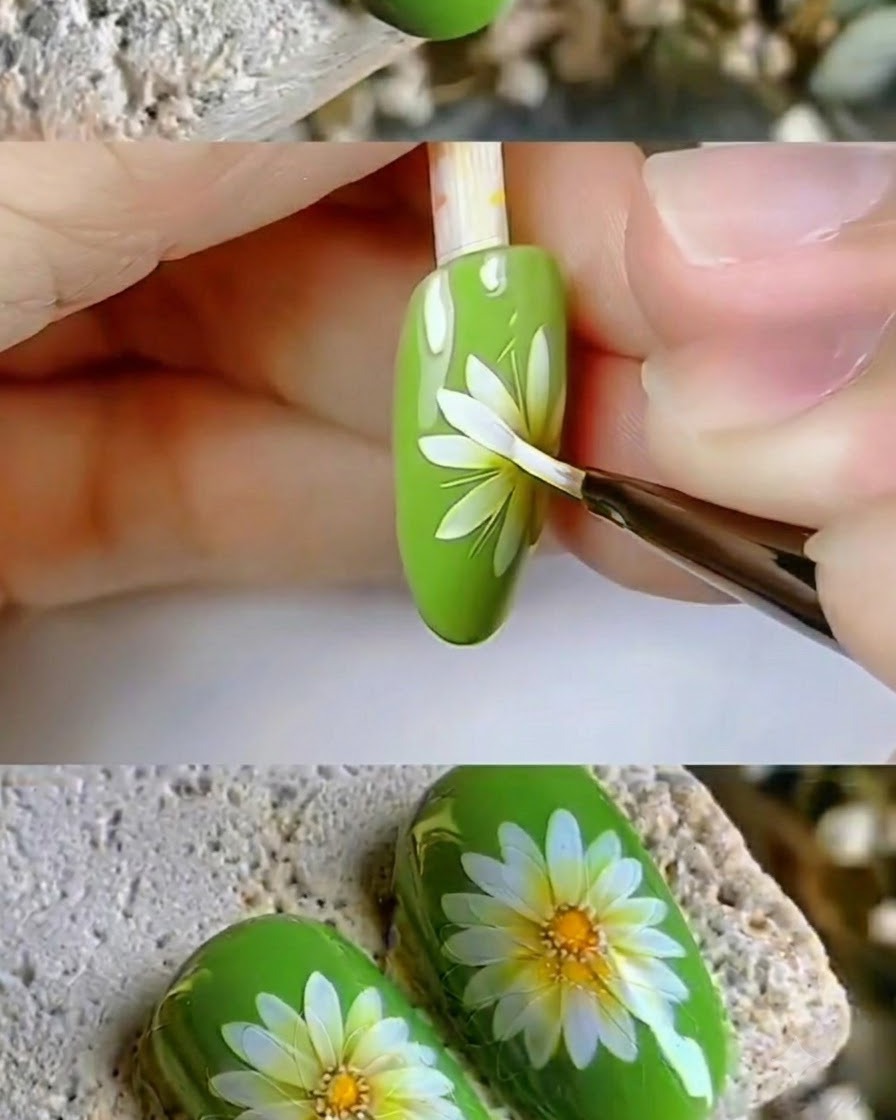 Ein feiner Detailpinsel überarbeitet die crisp weißen Blütenblätter eines Gänseblümchen-Nail-Art-Designs.
