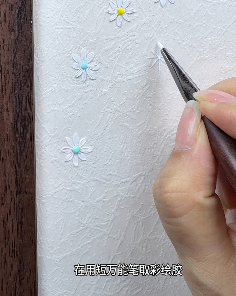 Eine Hand hält einen feinen Detailpinsel, der mit weißem Mal-Gel beladen ist, nahe einem strukturierten Hintergrund.
