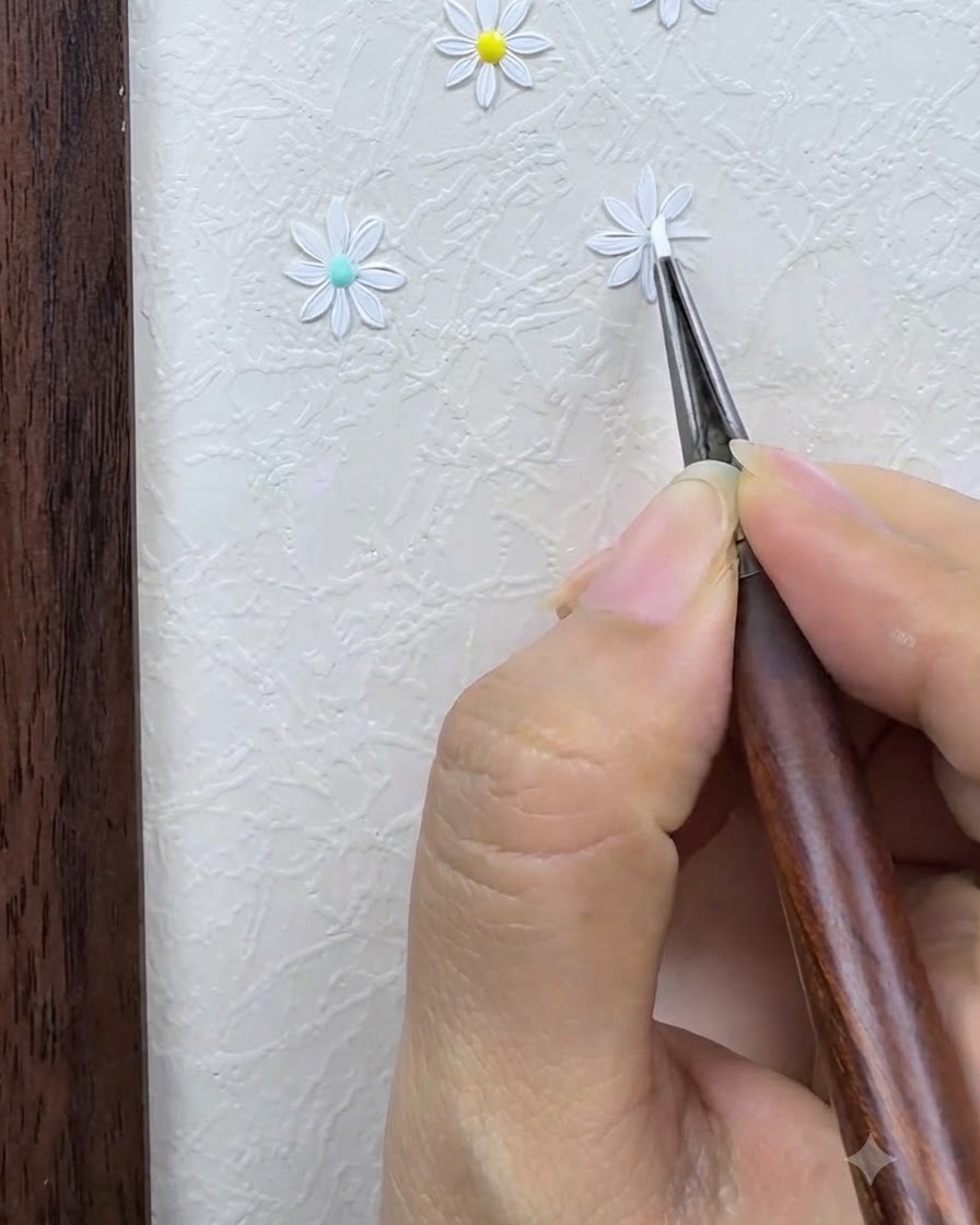 Ein Detailpinsel umrandet und verfeinert sorgfältig die weißen Blütenblätter eines gemalten Gänseblümchens vor einem strukturierten Nail-Art-Hintergrund.