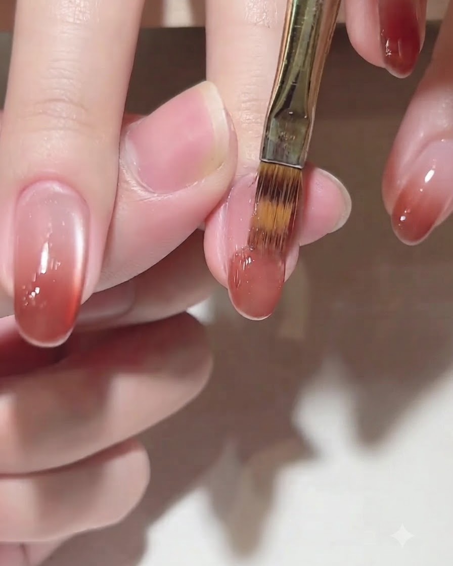 Ein Pinsel trägt Farbgel C102 auf die Nagelspitze auf, um einen Ombré-Effekt zu erzielen.