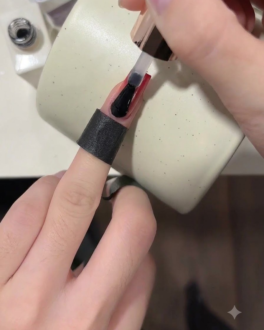 Ein Pinsel trägt einen klaren, glänzenden Top-Coat über einen fertigen weinroten Ombré-Nagel auf.