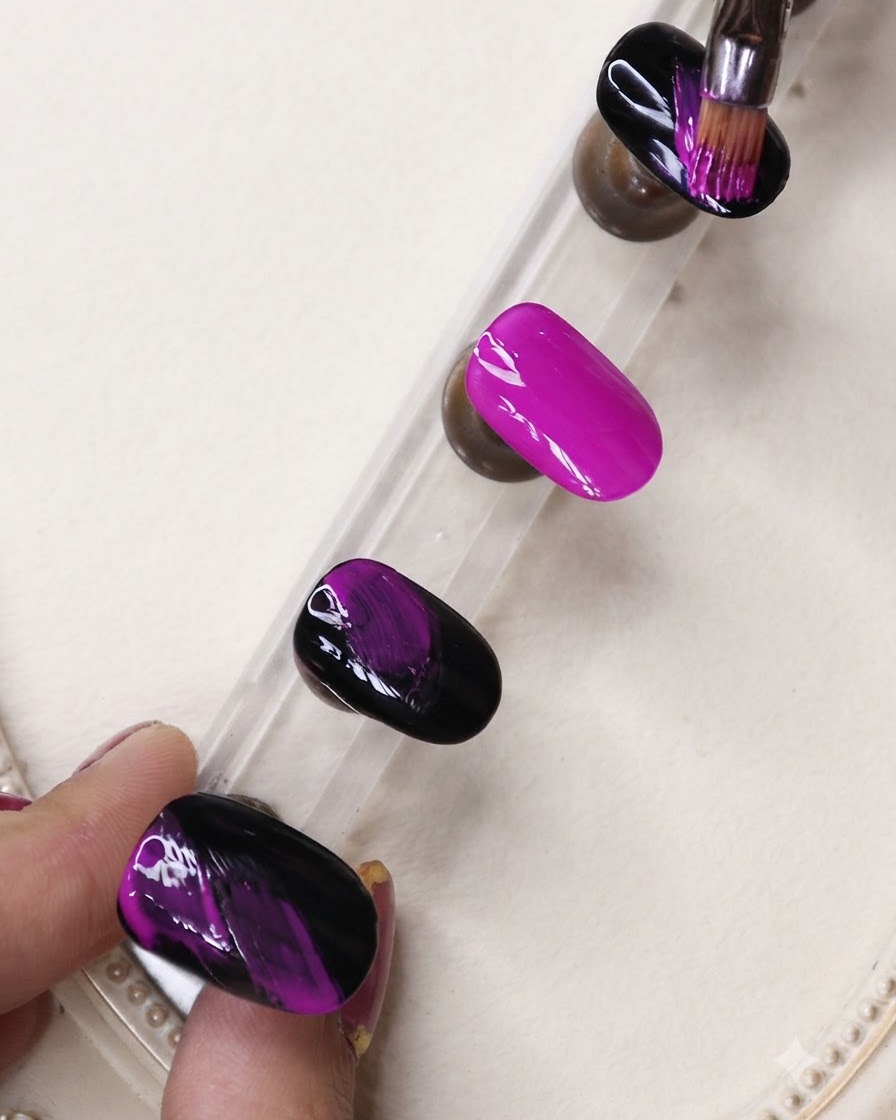 Ein feiner Liner-Pinsel trägt schwarze Gel-Striche auf einen leuchtend neonvioletten Nagel auf einem Präsentationsständer auf.