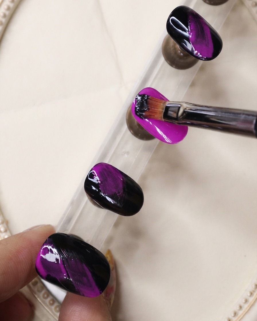 Ein feiner Liner-Pinsel trägt schwarzes Gel in strukturierten Strichen über einen neonvioletten Nagel auf.