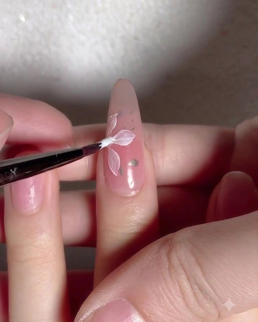 Ein Pinsel trägt eine klare, glänzende Top-Coat-Schicht über einen mit Blumen und Flocken verzierten Nagel auf.