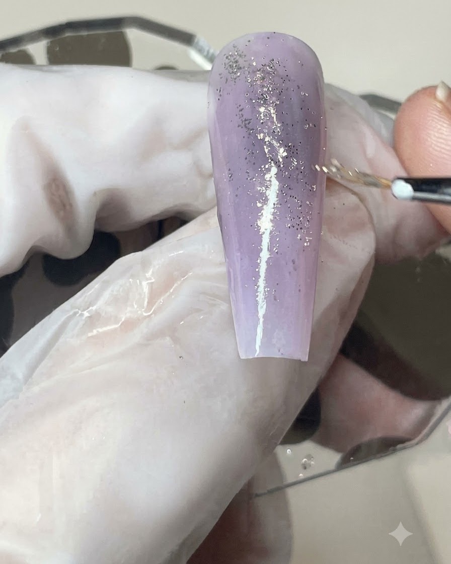 Ein Gelpinsel trägt eine gleichmäßige Schicht matten Top Coat über einen mit Glitzer versehenen lila Ombré-Nagel auf.