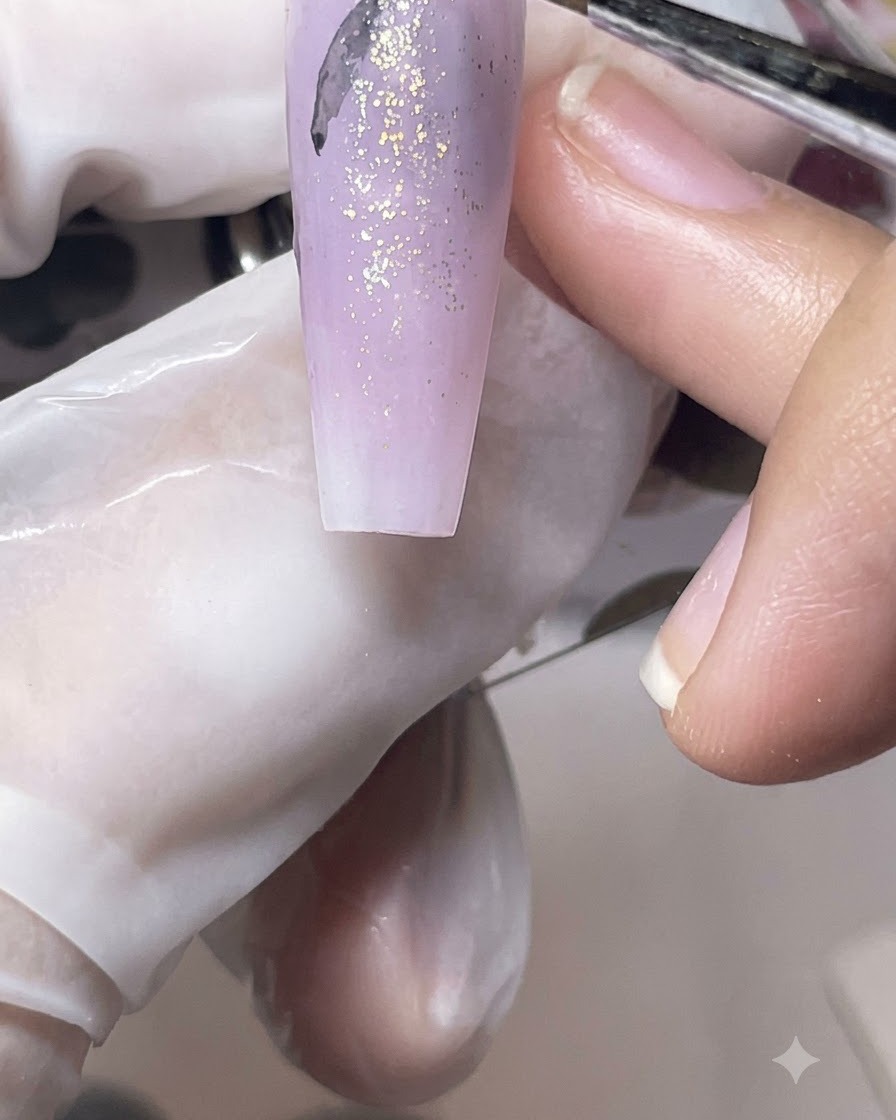 Ein feiner Liner-Pinsel zeichnet zarte schwarze Schmetterlingssilhouetten auf eine lila matte Nagelspitze.