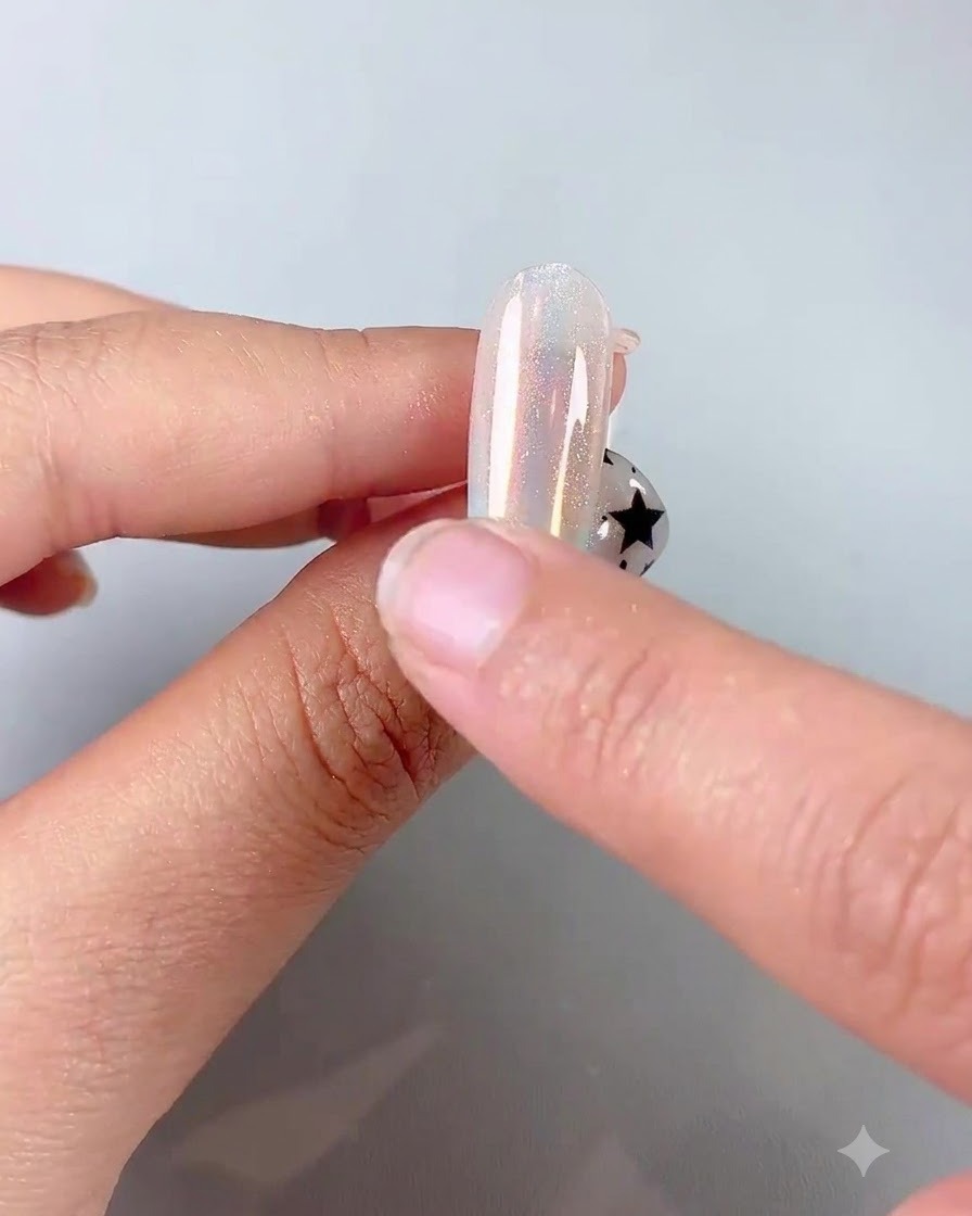 Ein Finger verwendet einen Silikonschwamm-Applikator, um irisierendes Chrompuder auf einen glänzenden Nagel zu reiben.