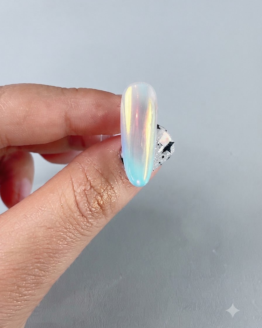 Eine Nahaufnahme eines fertigen irisierenden Aurora-Chrom-Nagels mit einer lebendigen, mehrfarbigen Spiegelreflexion.
