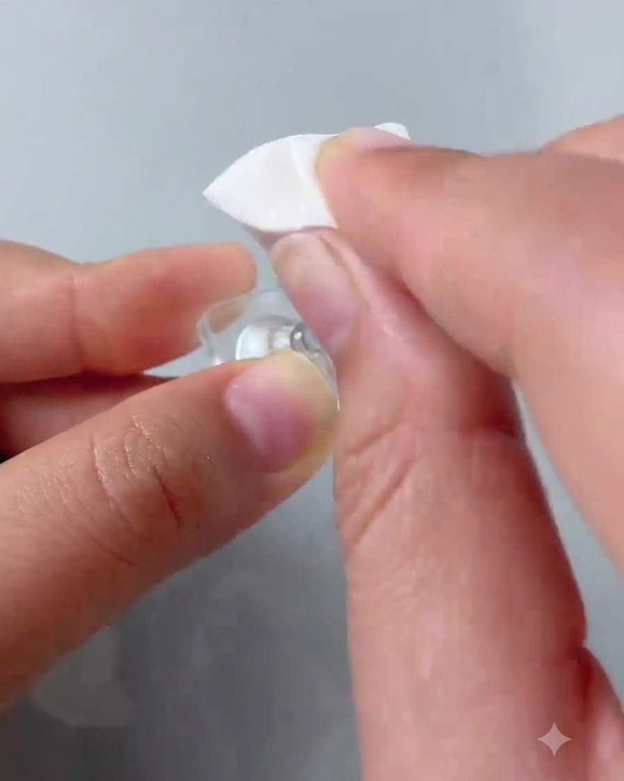 Ein Schwämmchen-Applikator tupft rosafarbenes Gel-Polish auf die Spitze eines klaren Übungsnagels.