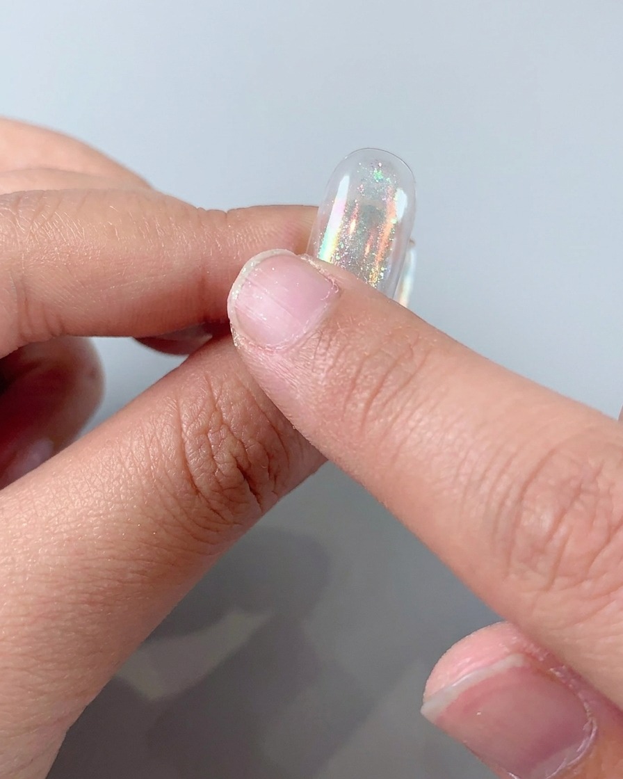Holografisches Aurora-Puder wird auf einen Nagel gerieben, um ein glänzendes metallisches Finish zu erzeugen.