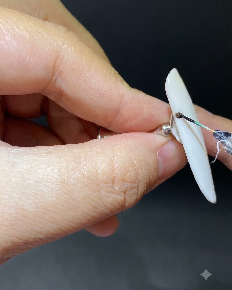 Ein feiner Pinsel zeichnet einen dunklen, geschwungenen Zweig von der Nagelhaut auf einen Ombré-Nagel.