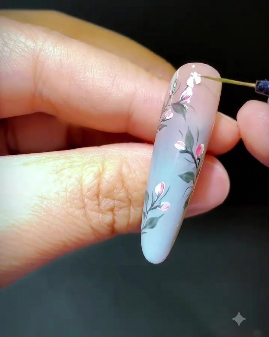 Ein Werkzeug platziert zerkleinerte Muschelsplitter auf nassem Gel, um ein florales Design zu formen.