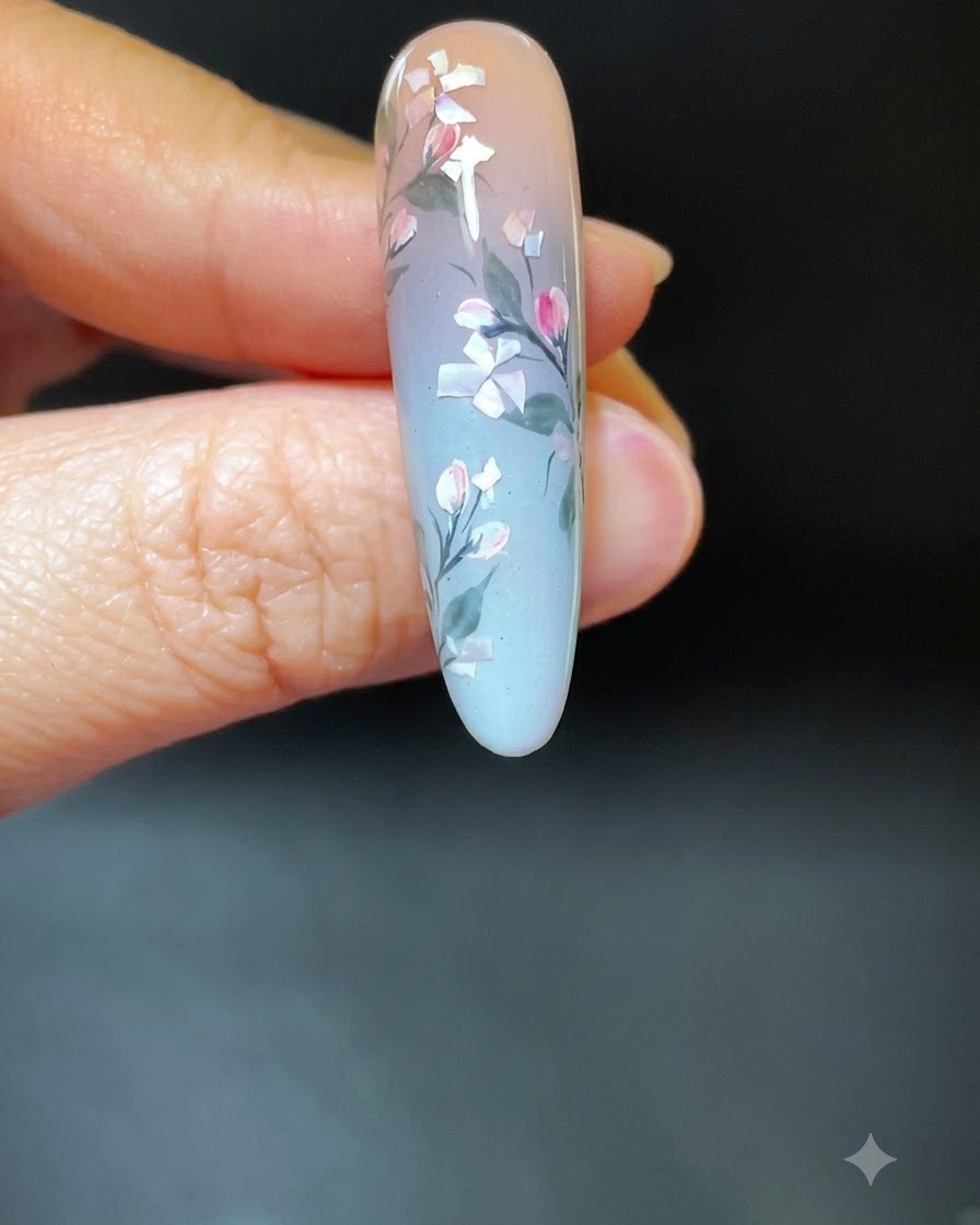 Eine Hand mit fertiger Muschel-Blumen-Nailart in einer weißen UV/LED-Härtungslampe.