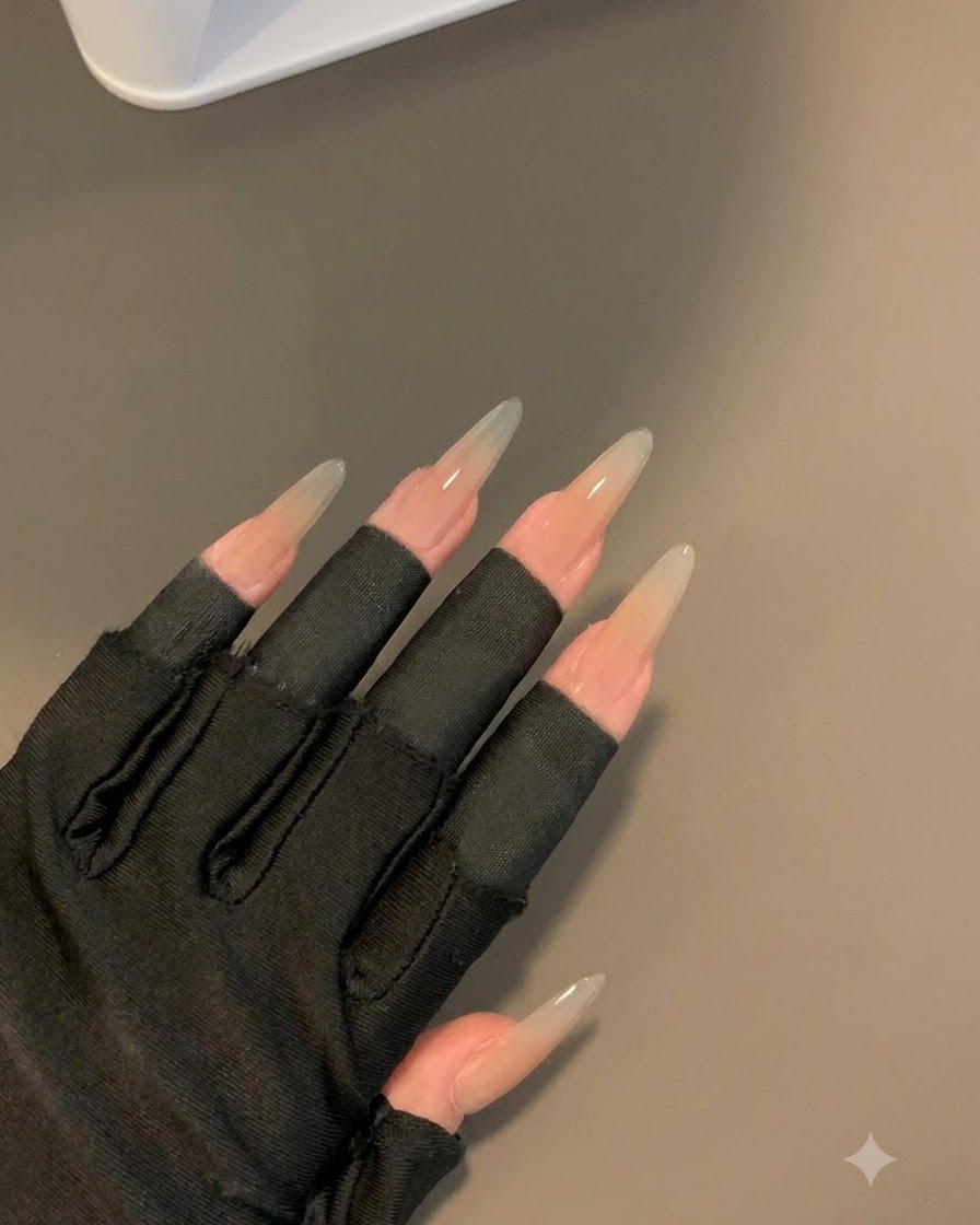 Eine behandschuhte Hand mit schwarzen fingerlosen Ärmeln zeigt die ausgehärteten Nägel nach 30 Sekunden unter einer Lampe.
