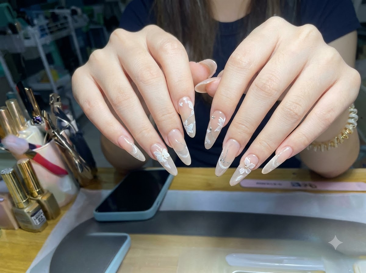 Ein makrofokussierter Blickwinkel zeigt die Glitzer-Cat-Eye-Schicht und die 3D-Blumenmuster auf mandelförmigen Fingernägeln.