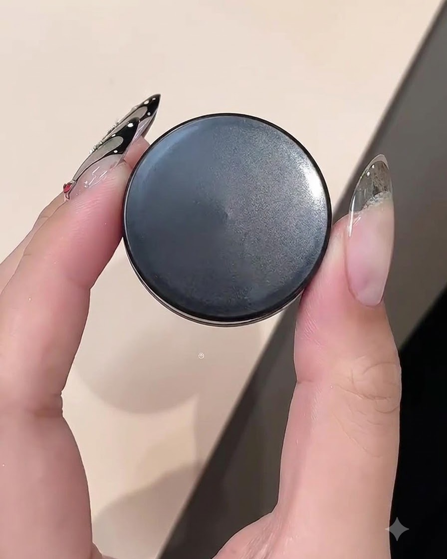 Nahaufnahme einer Hand, die einen Tiegel Clay Gel hält, während sie an einer Nagelkante arbeitet.