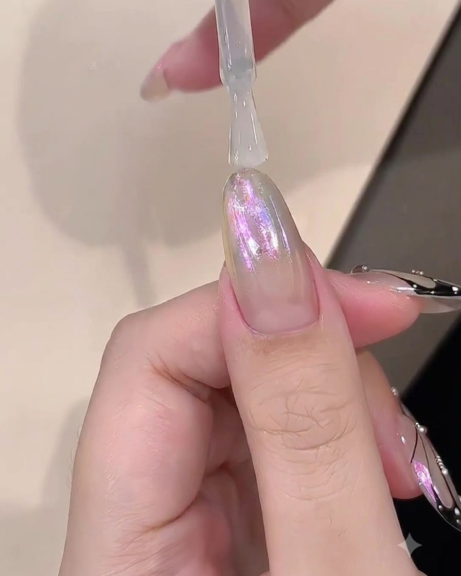 Ein Pinsel trägt eine klare Schicht Aufbaugel über einen chromveredelten Nagel auf.