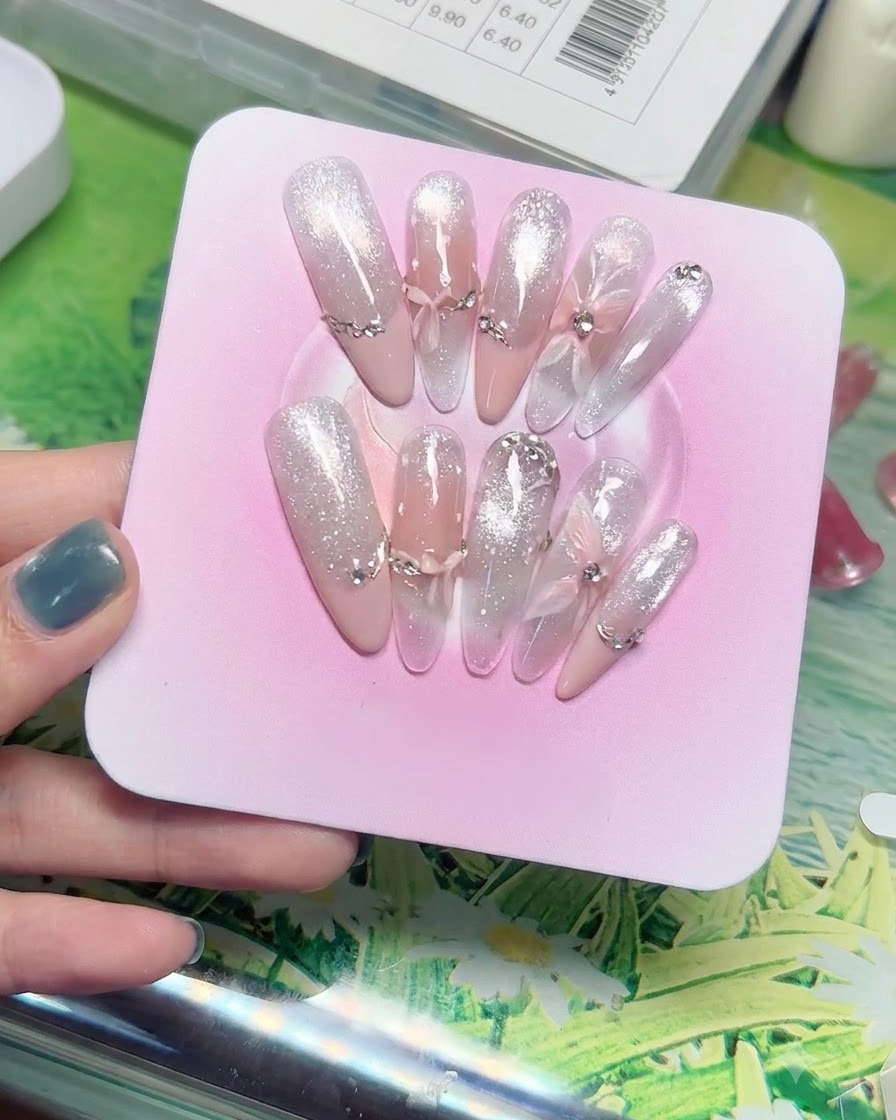 Makroaufnahme von geschichteten, transparenten Schleier-Schmetterlings- und Schleifenanhängern auf durchscheinenden Farbverlauf-Nagelspitzen.