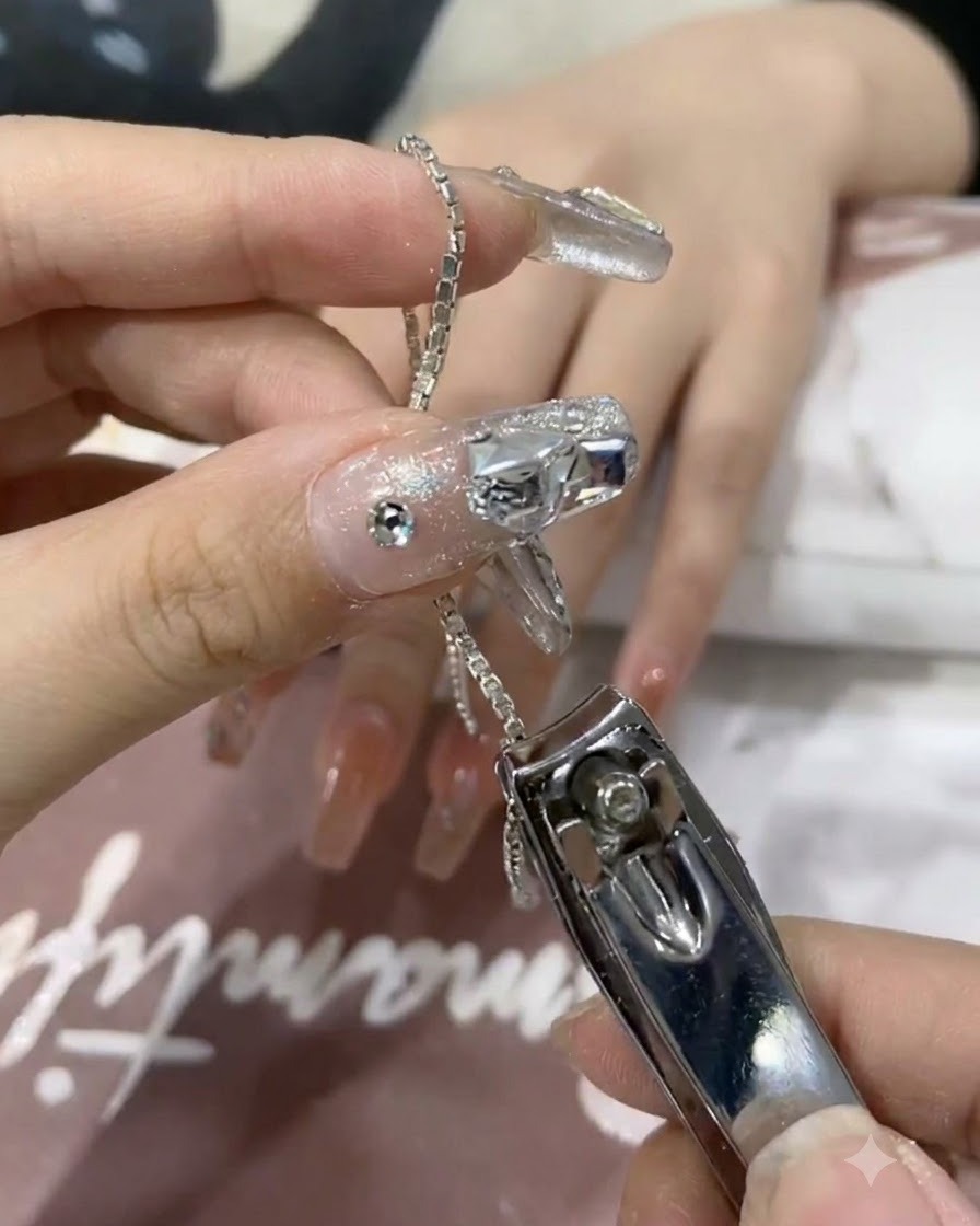 Eine Nahaufnahme von Nagelknipsern, die ein kleines Stück glänzende Silberkette abschneiden.