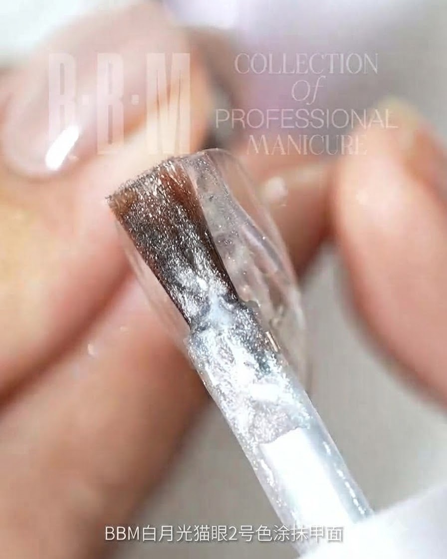 Ein Nagelpinsel trägt silbernes Glitzer-Cat-Eye-Gel auf eine klare Nageloberfläche auf.