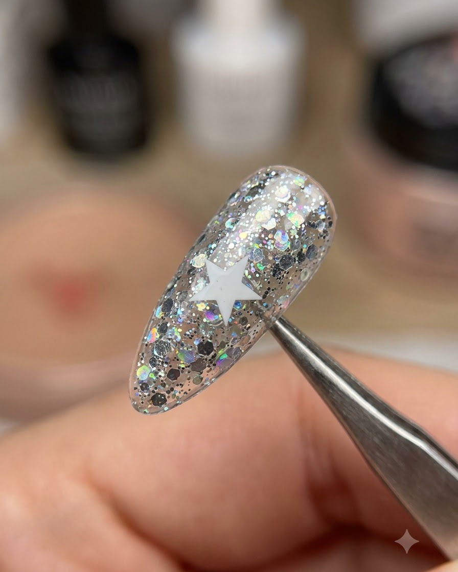 Eine Pinzette hebt einen weißen Sternaufkleber von einem schimmernden Glitzernagel ab.