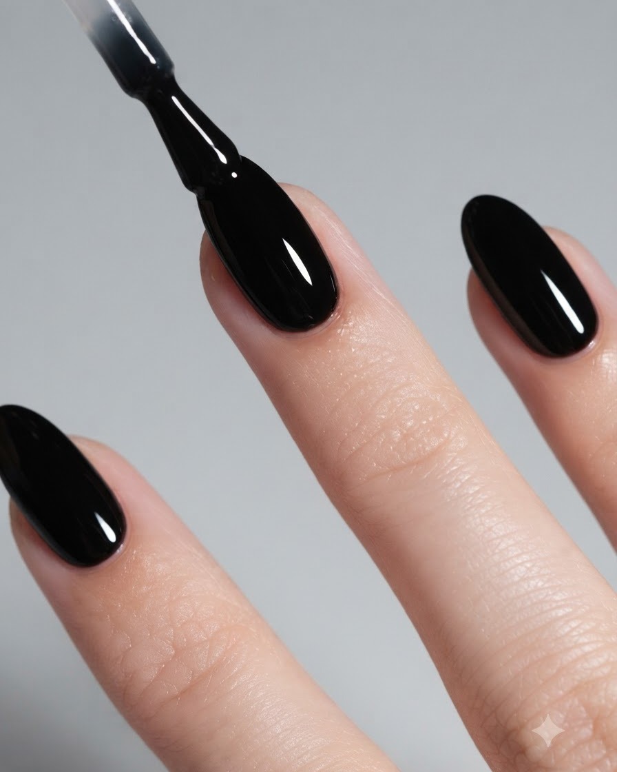 Nahaufnahme eines Pinsels, der glänzenden schwarzen Gel-Nagellack auf einen mandelförmigen Nagel aufträgt.