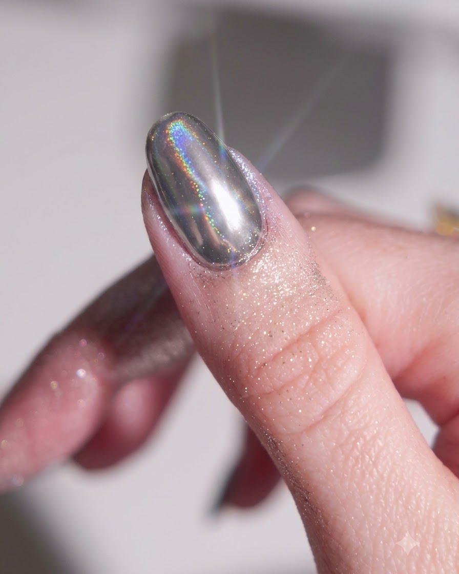 Ein Finger mit ausgehärtetem schwarzem Basis-Gel, in das ein silbernes Chrom-Puder mit einem Silikonschwamm-Applikator eingerieben wird.