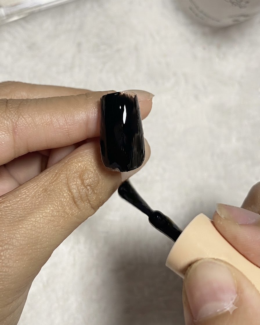 Ein Nagelpinsel trägt eine glatte Schicht schwarzen Gel-Lacks auf eine Nagelverlängerung auf.