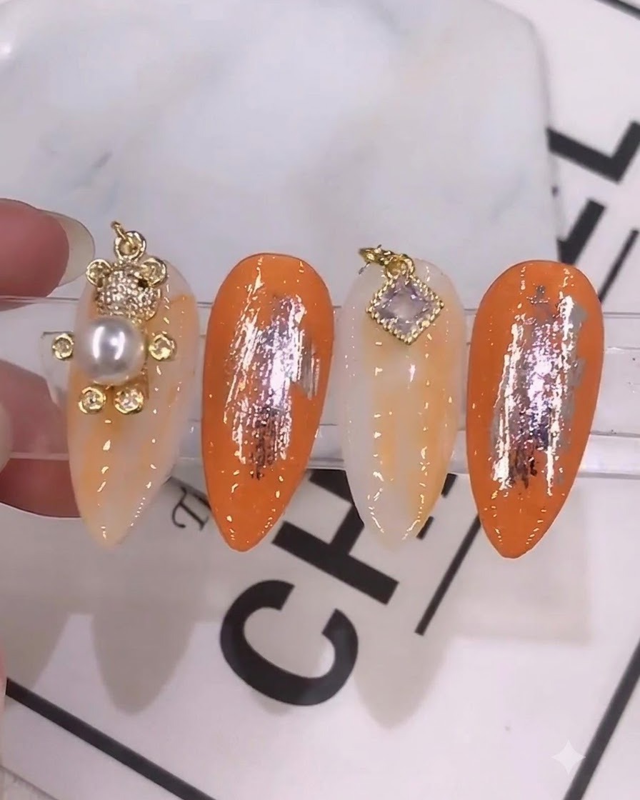 Eine detaillierte Nahaufnahme, bei der ein Nagelpinsel eine lebendige, orangefarbene Gel-Mischung auf einen vorbereiteten Nagel aufträgt.