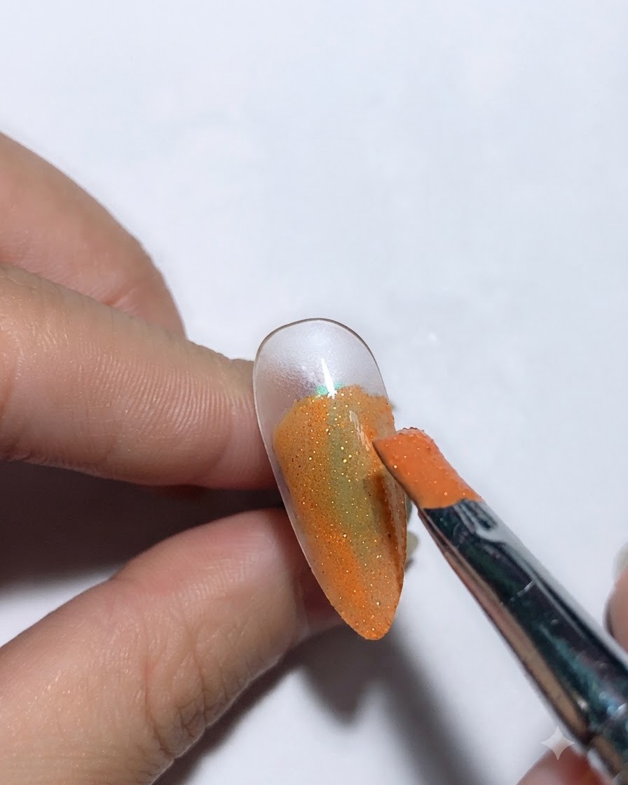 Ein Pinsel trägt Sternenhimmel-Kleber über einer orangefarbenen Nagelbasis auf.