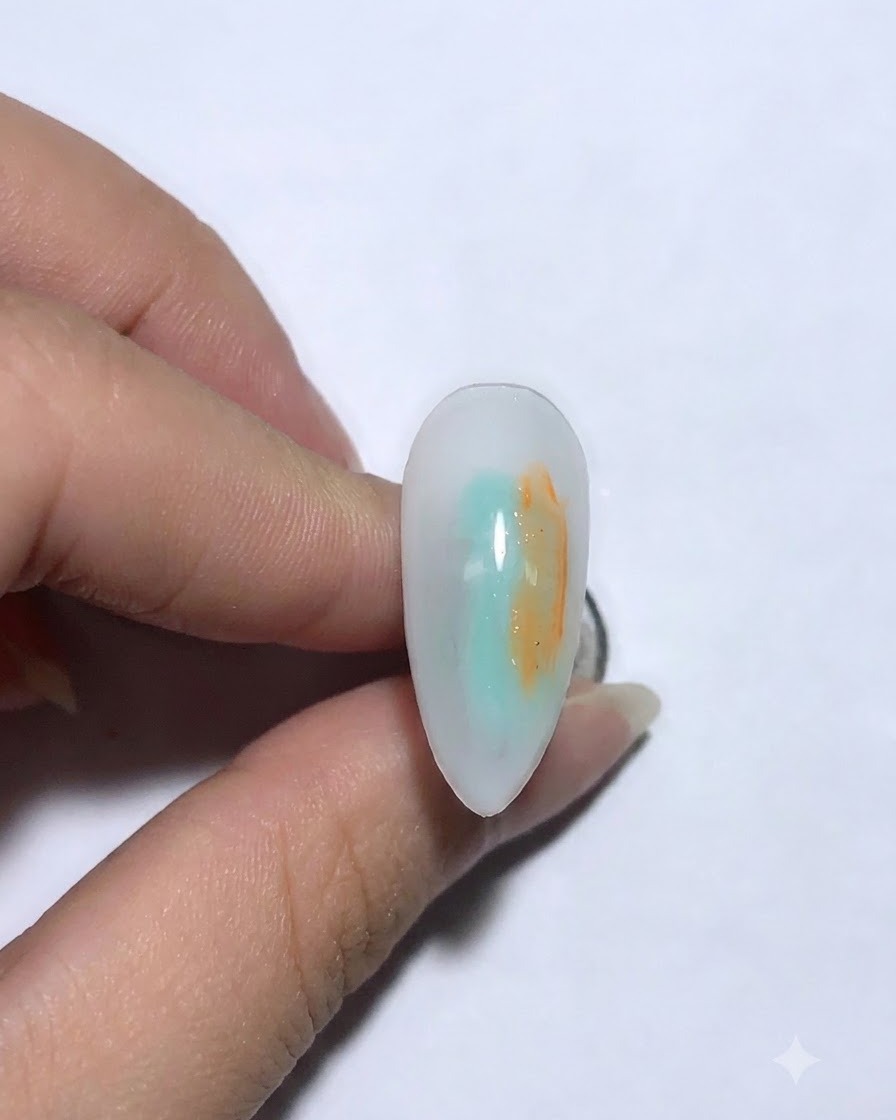 Eine Nahaufnahme eines dekorierten Nagels mit einem angebrachten Bären-Strass- und Ketten-Accessoire.