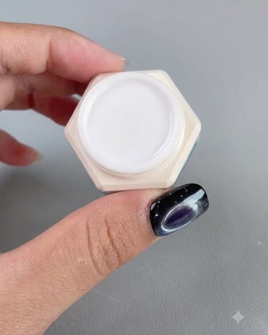 Ein Tiegel mit hochtransparentem bernsteinfarbenem Nagelgel neben einem manikürten Finger.