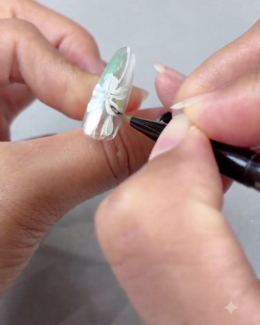 Ein Nagelpinsel verblendet zart Bernsteingel-Schattierungen über weiß gemalten Lilienblättern.
