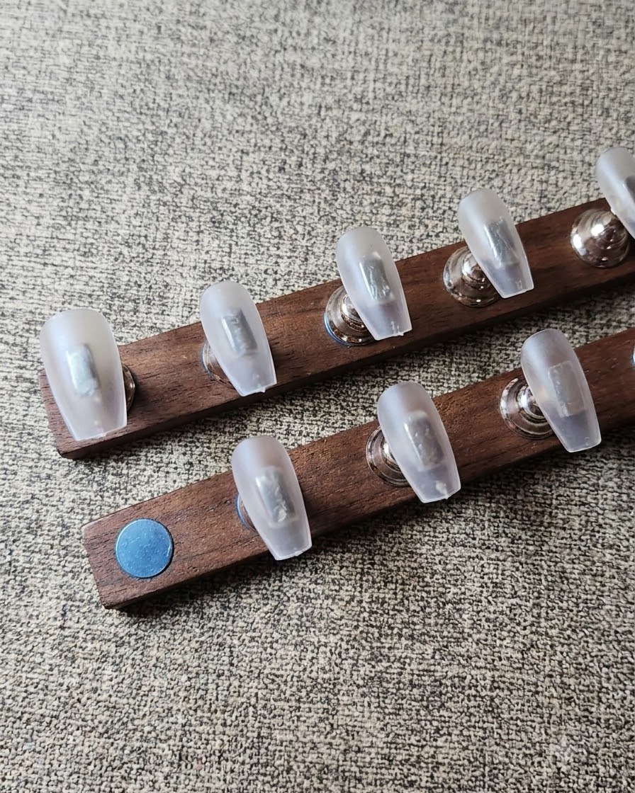 Eine fusselfreie Zellette reinigt den Staub von vorbereiteten klaren Nageltips auf einem Holzständer.