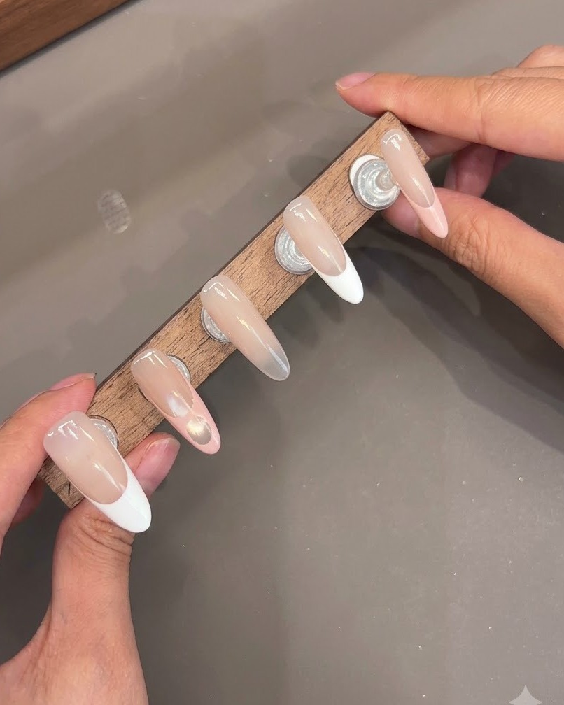 Mehrere Press-On-Nägel auf einem Holzständer zeigen glänzende Top-Coat-Schichten.