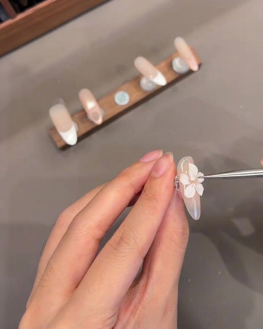 Nahaufnahme eines dünnen Werkzeugs, das ein kleines weißes Gelzentrum auf einer 3D-Blüte platziert.