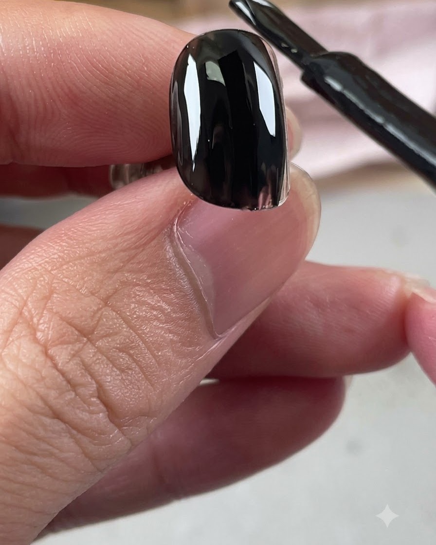 Ein Pinsel einer schwarzen Gelpolitur trägt eine glänzende Schicht schwarzen Unterlack auf einen Nagel auf.
