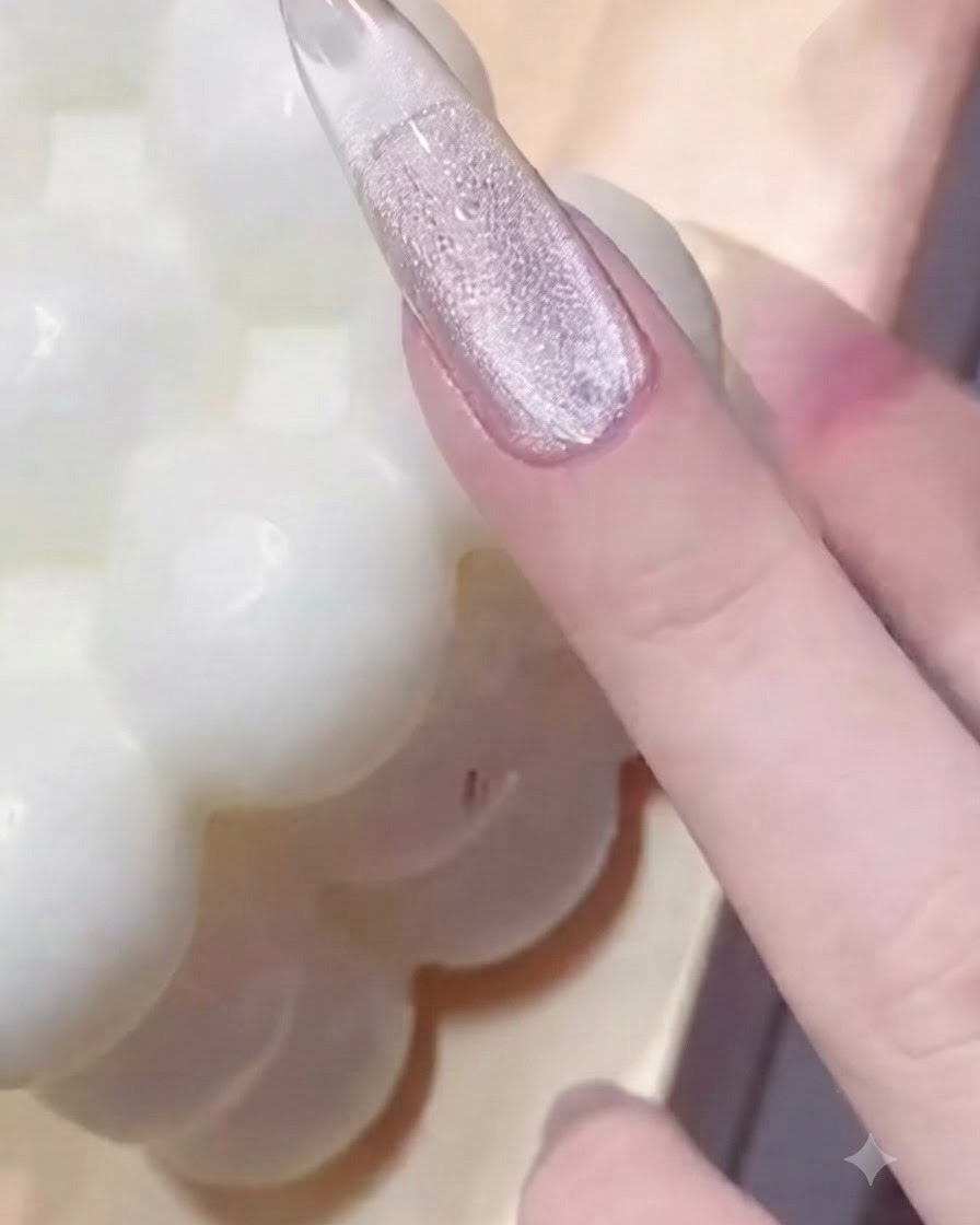 Eine Hand drückt ein Perlenring-Werkzeug auf einen glänzenden, mit Gel überzogenen Fingernagel, um strukturierte Abdrücke zu erzeugen.