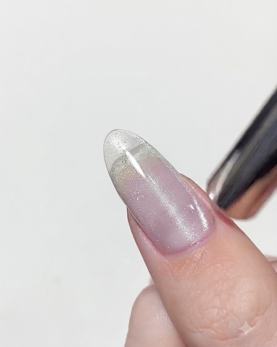 Ein Magnetwerkzeug wird nah über einen feuchten Cat-Eye-Nagel gehalten, um den silbernen Schimmer zu einer vertikalen Linie zu bündeln.