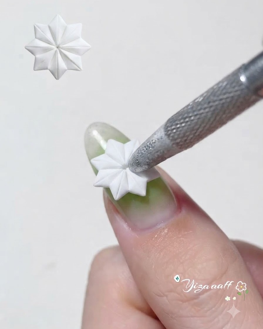 Ein Pinsel oder Werkzeug verteilt transparentes grünes Gel gleichmäßig über einer silbernen Cat-Eye-Nagelbasis.