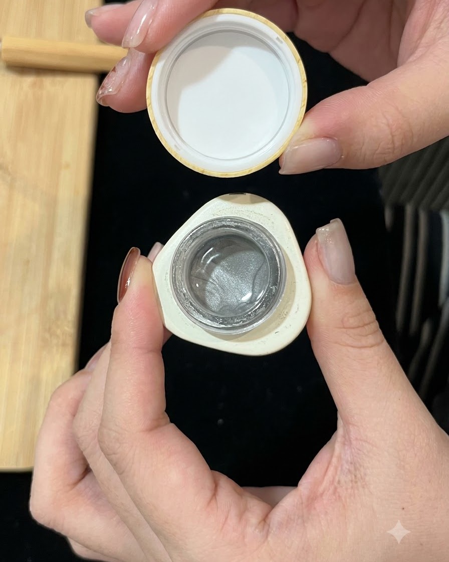 Ein kleiner geöffneter Tiegel mit silbernem, magnetischem Cat-Eye-Gel, der die schimmernde Formel zeigt.