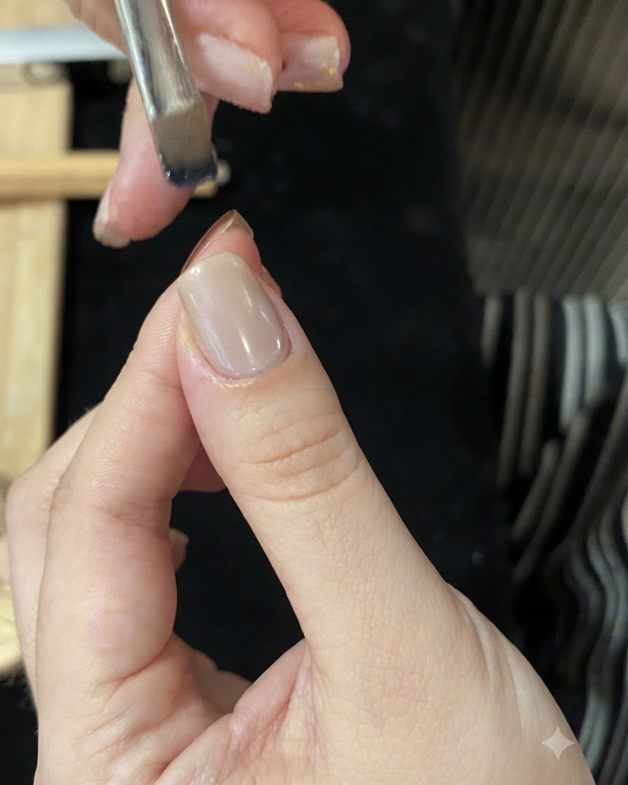 Ein mit blauem Glasgel benetzter Pinsel über einer Nagelspitze, um einen Ombré-Verlauf zu kreieren.