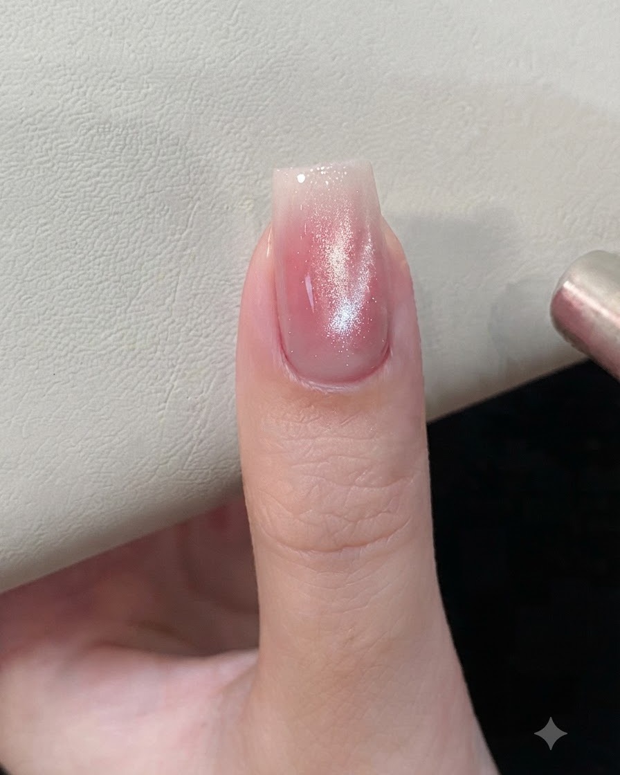 Ein Magnetwerkzeug wird nahe an einen rosa-silbernen Cat-Eye-Gel-Nagel gehalten, um die magnetischen Partikel zu formen.