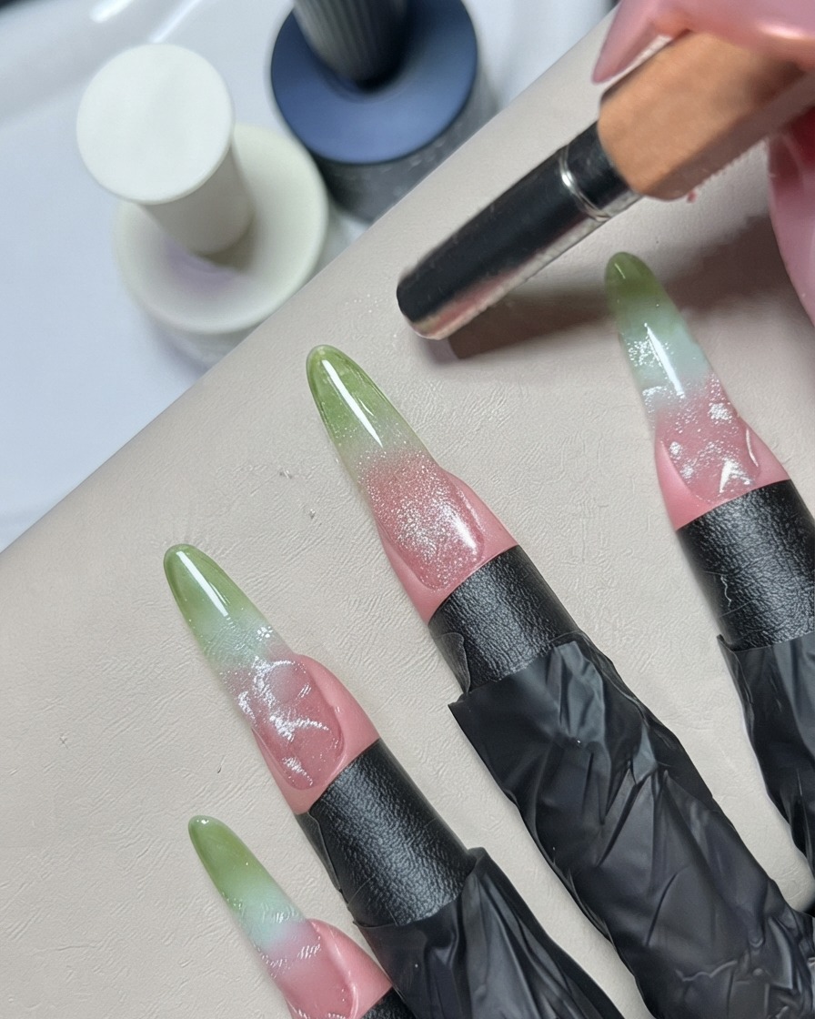 Ein Dotting-Tool oder Metall-Detailing-Werkzeug verblendet silberne Gel-Details auf einem dekorierten Nagel.