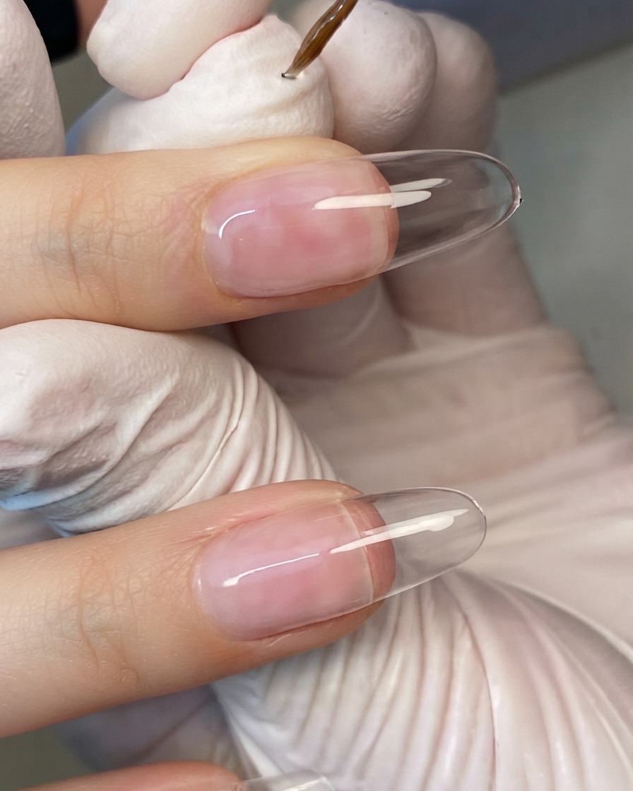 Eine Hand positioniert sich unter einer kompakten UV-Nagellampe, wobei die Finger von LED-Licht bestrahlt werden.