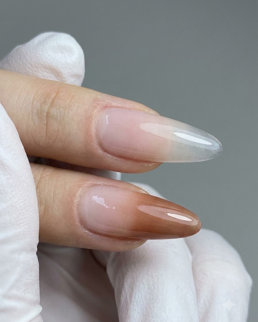 Ein Detailpinsel trägt peachy-nude Farbgel auf die untere Hälfte eines verlängerten klaren Nagels auf.