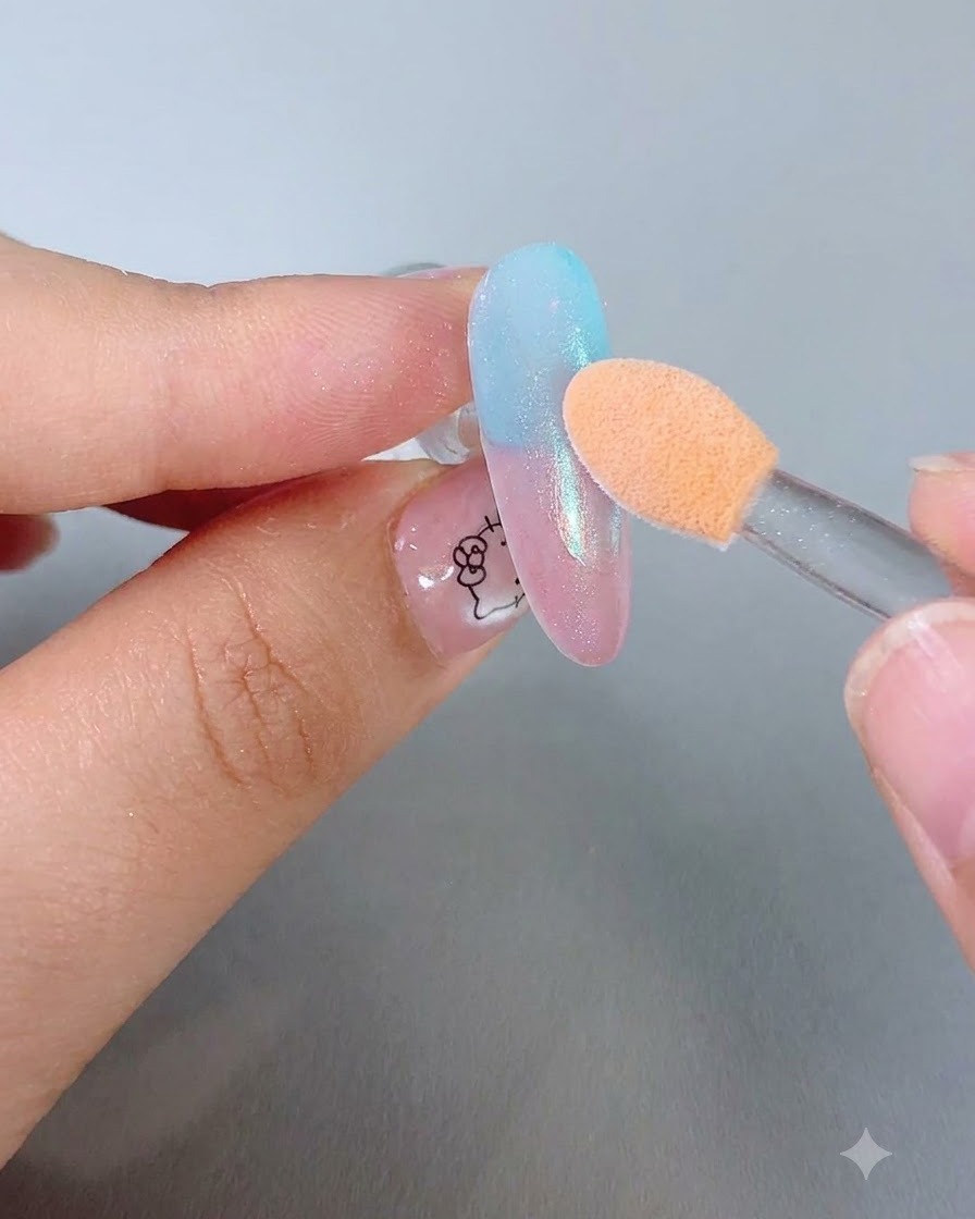 Ein Orangen-Schwamm-Lidschattenapplikator poliert glitzerndes Pulver auf einen glänzenden Farbverlaufsnagel.