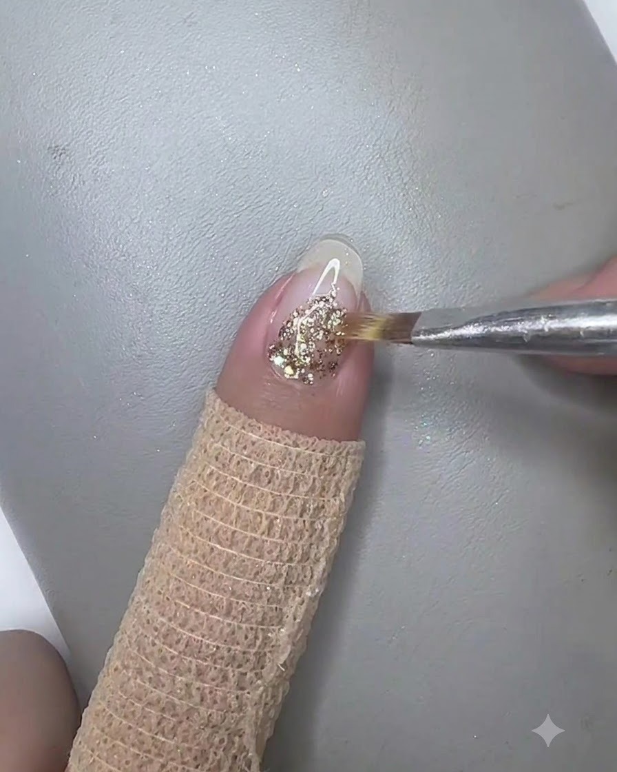 Ein feiner Liner-Pinsel zieht Goldglitter-Gel sanft nach unten in die Mitte der Nagelplatte.