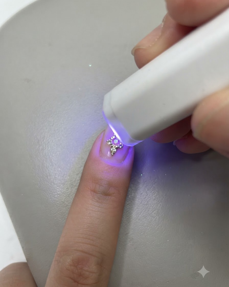 Eine kleine portable UV-LED-Lampe härtet einen fertig dekorierten Nagel an einem Finger aus.